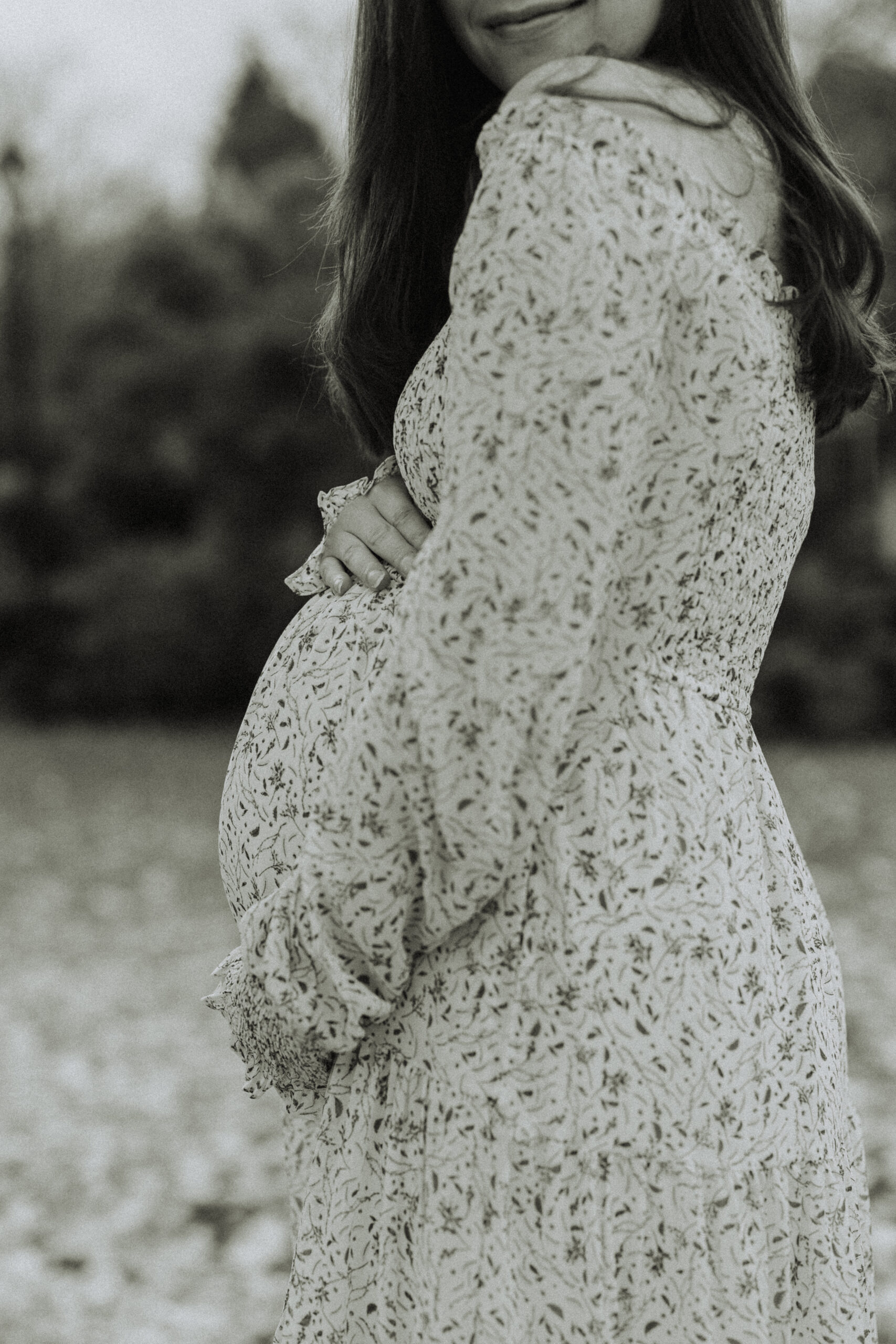 black and white photo of a close up of a mom cradling her baby bump in a fall landscape taken in langley