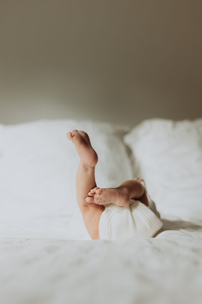 Photo of a newborn babys feet while they are laying on a big bed with white sheets taken in langley