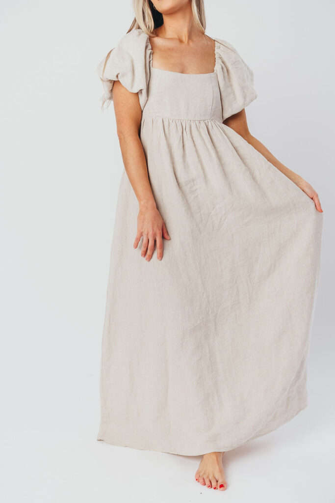 photo of a model wearing an off white linen short sleeve maternity photoshoot dress taken on a white background