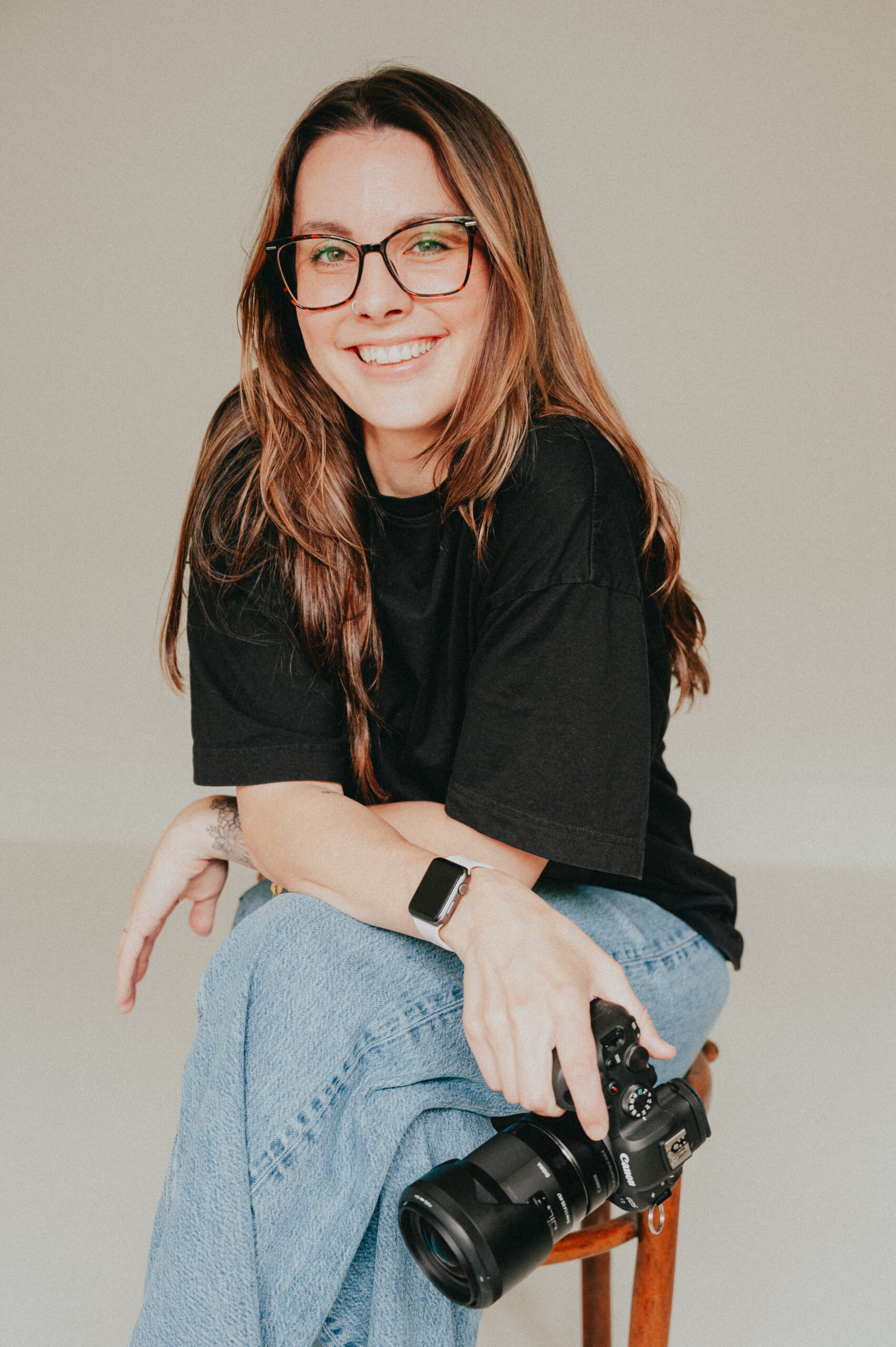 photo of a female photographer sitting on a chair holding her camera with a white background taken in langley