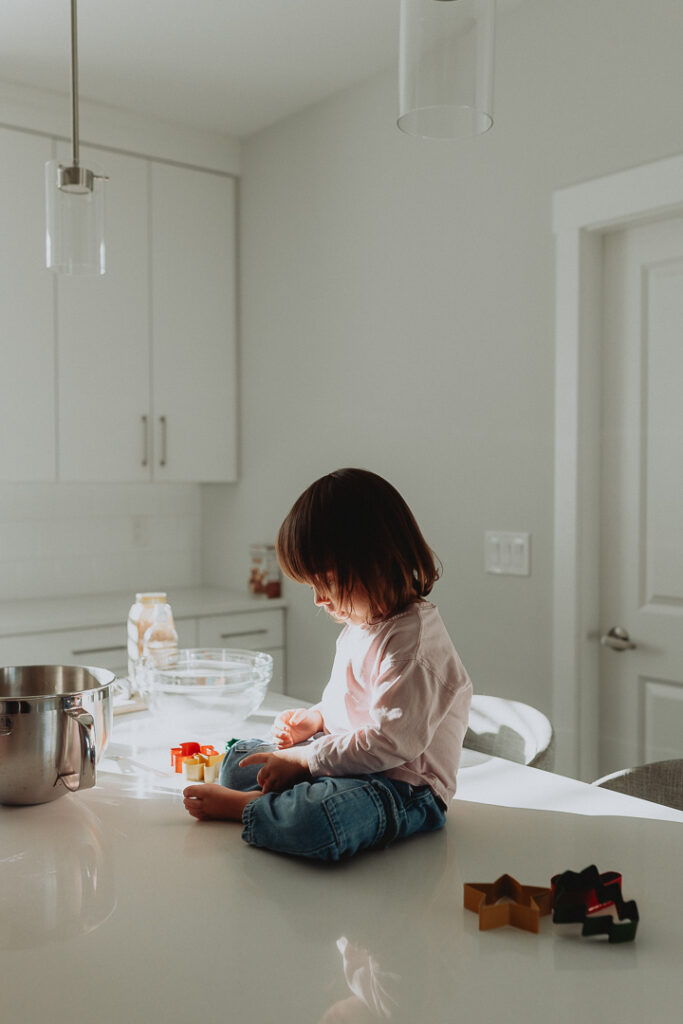 photo of a little girl sitting on the kitchen island playing with cookie cutters as a part of family photography taken in langley