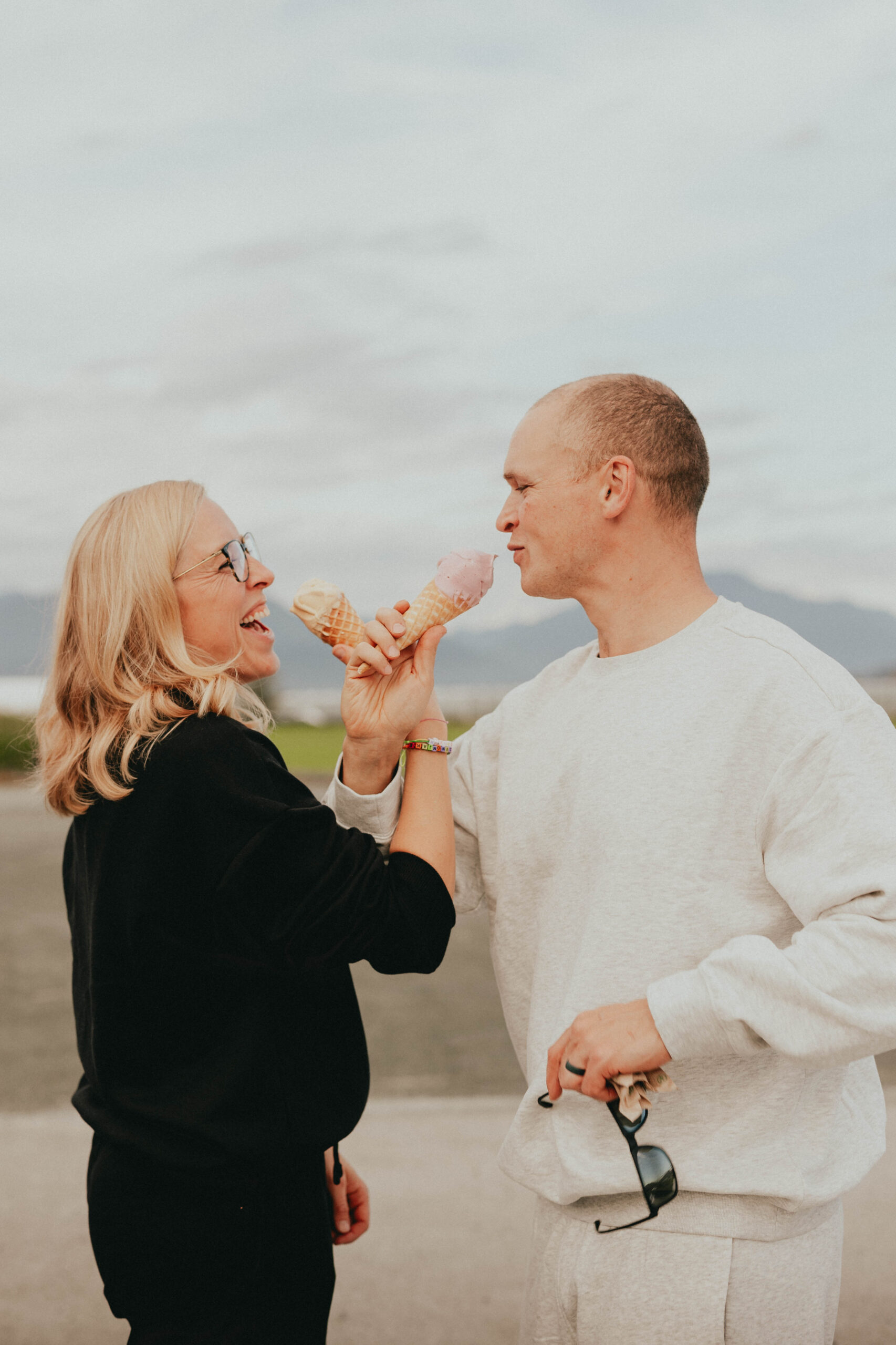 photo of a couple taken outside in Langley. They have their arms hooked while holding ice cream and are smiling at each other