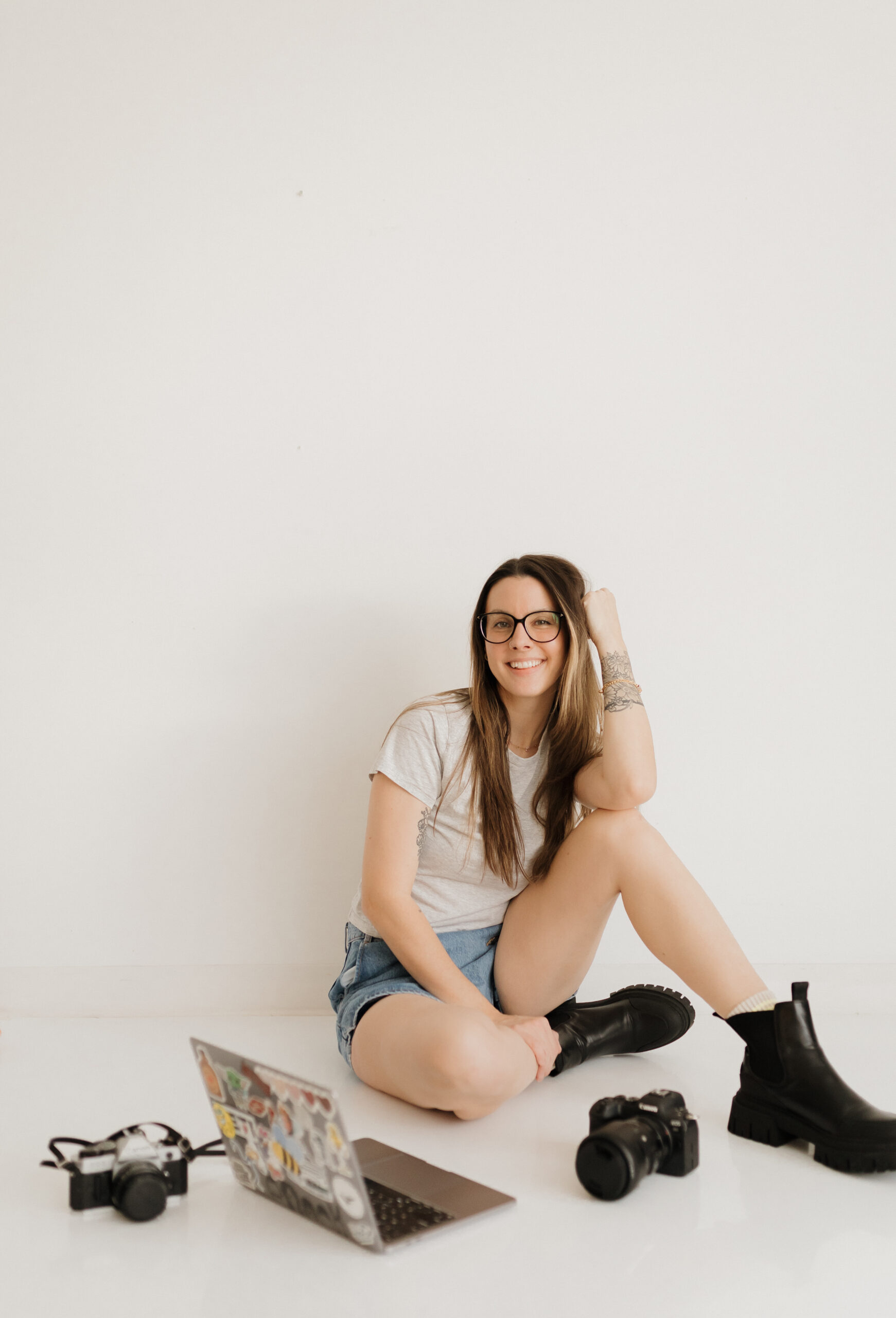 photo of a langley family & newborn photographer smiling at the camera with her gear on the floor around her