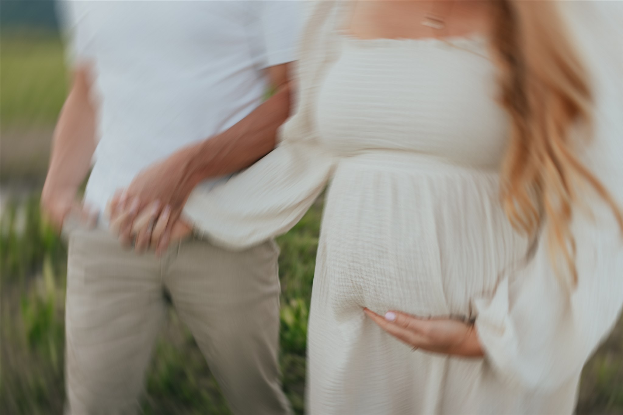 blurred photo of a couple holding hands and the woman holding her baby bump, their faces are not in the photo. Taken by a langley family & newborn photographer