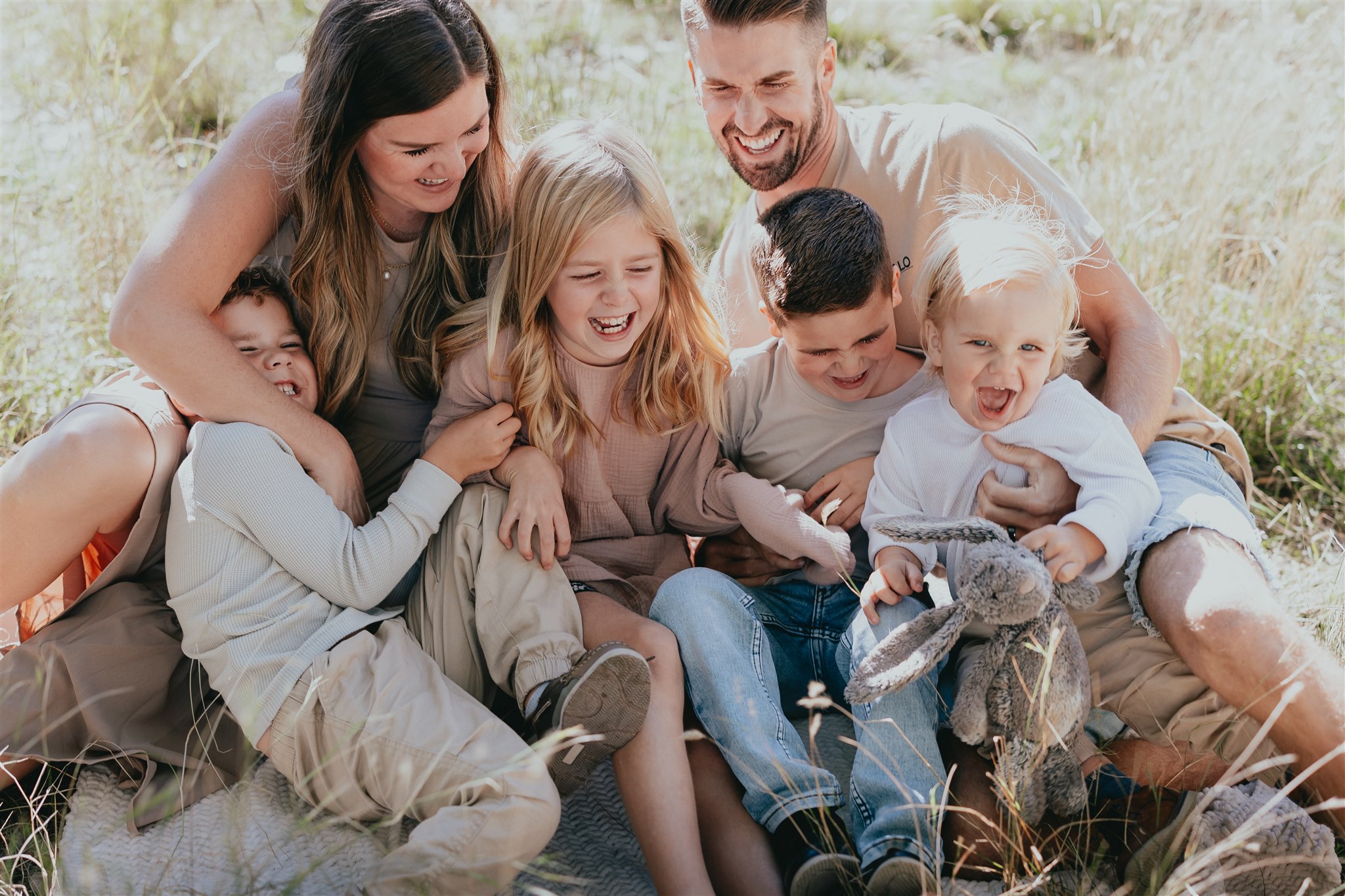 Photo of a family all tickling each other and laughing taken outdoors. Taken by a langley family & newborn photographer