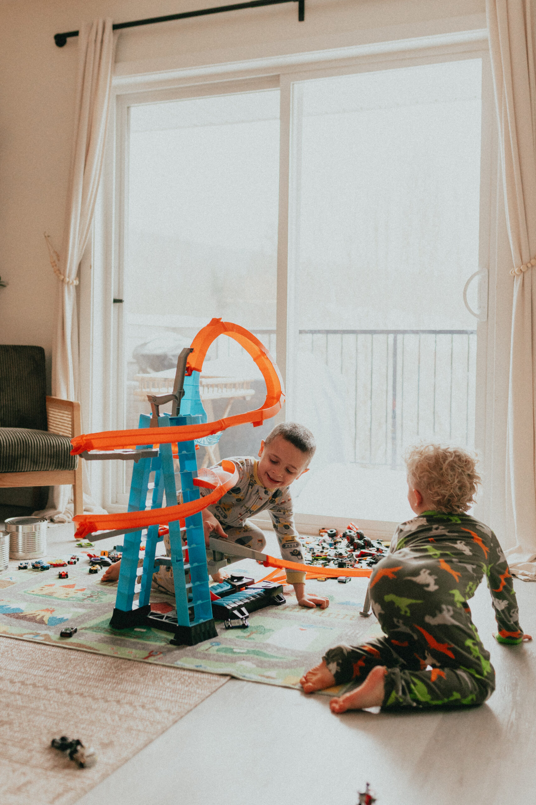 photo of 2 little boys in their pjs playing with their hot wheels cars and track and participating in indoor family activities