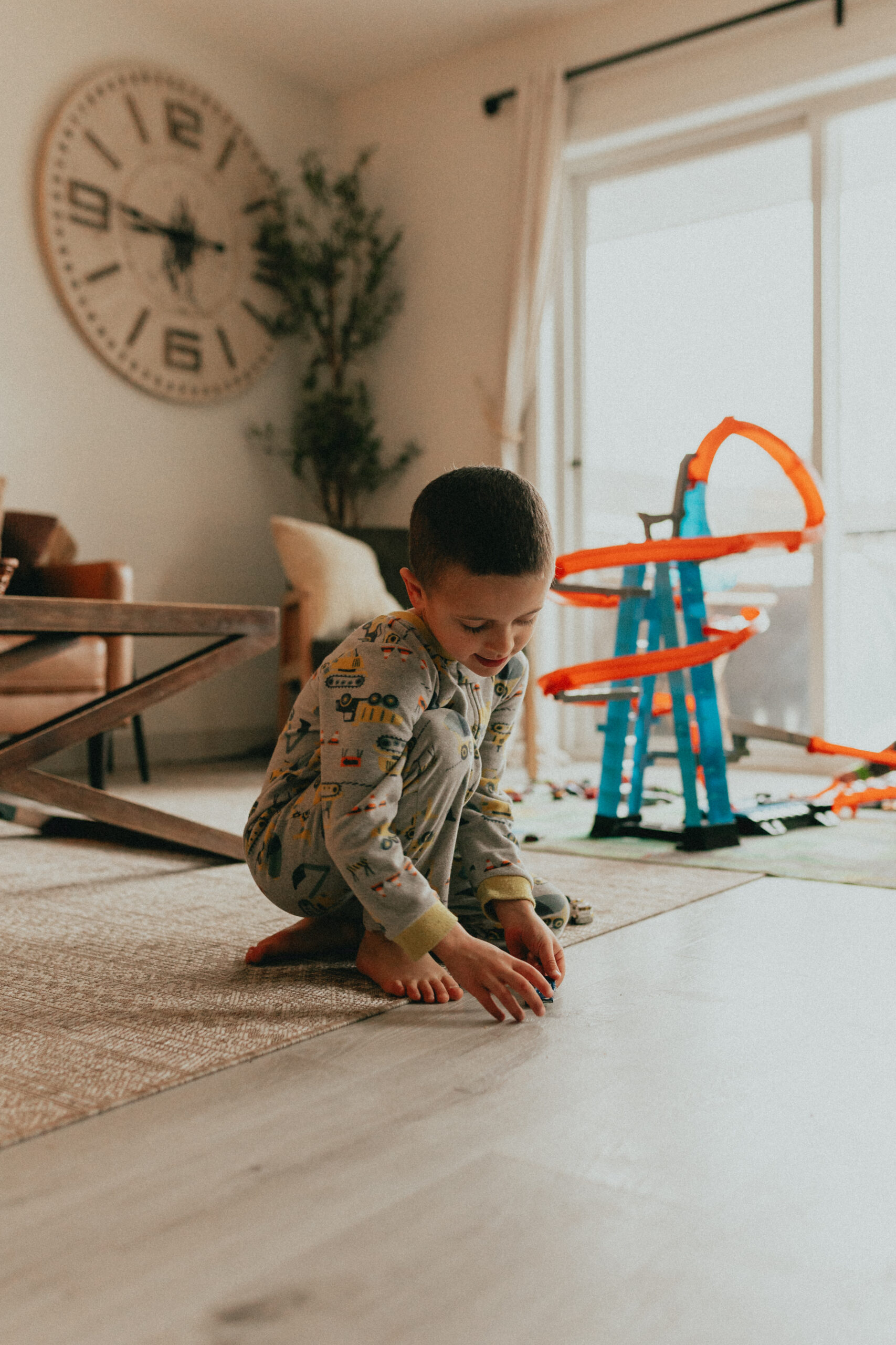 photo of a boy sitting in front of his race track participating in indoor family activities like playing cars. 