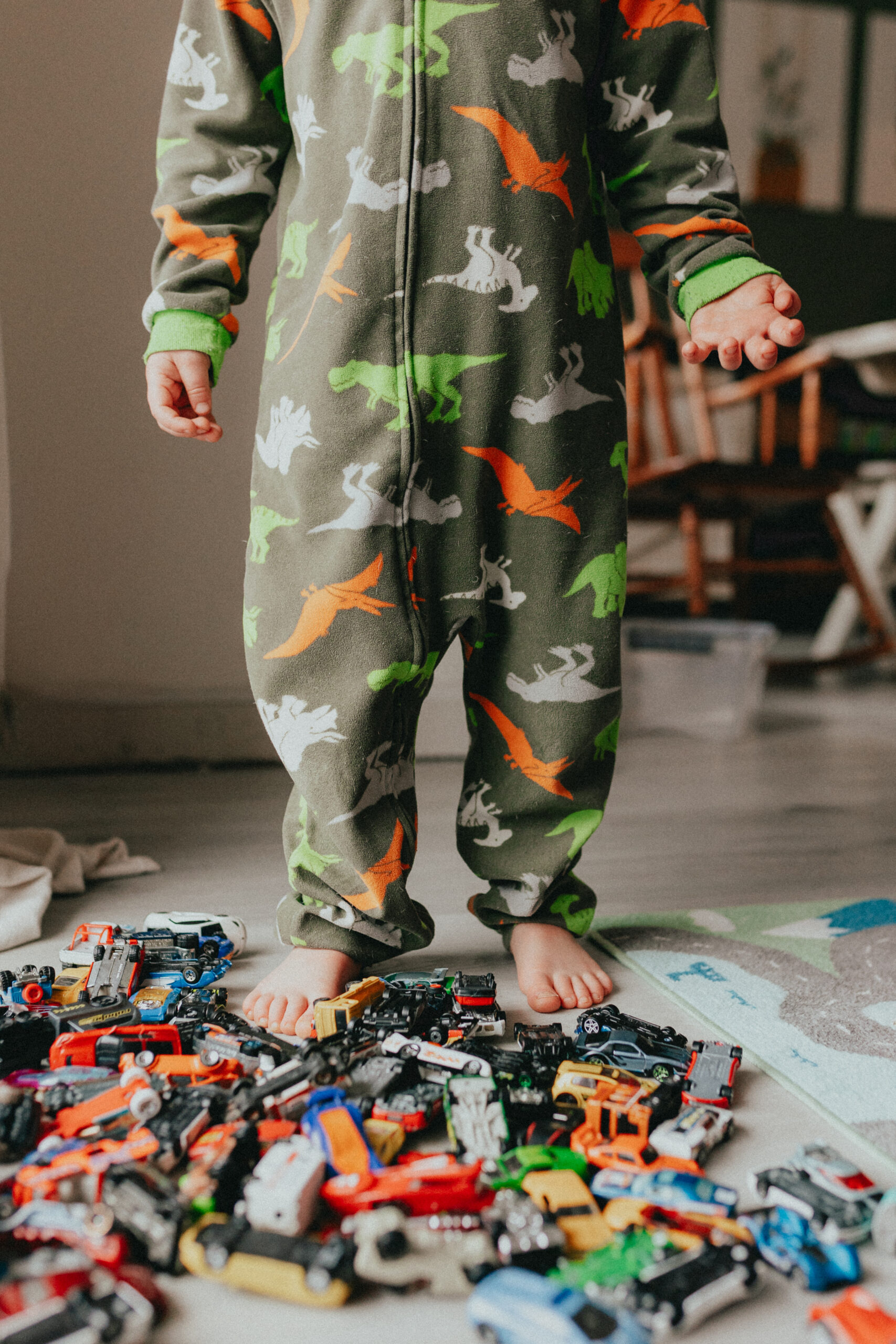 photo of a little boy in pjs taken from the shoulder down with bare feet and his cars all around his feet