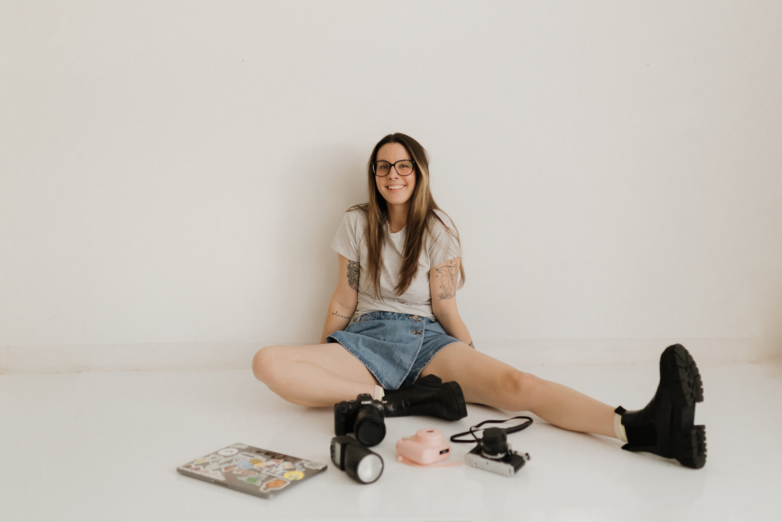 photo of a langley family and newborn photographer sitting on the ground with her gear around her on the floor while smiling at the camera