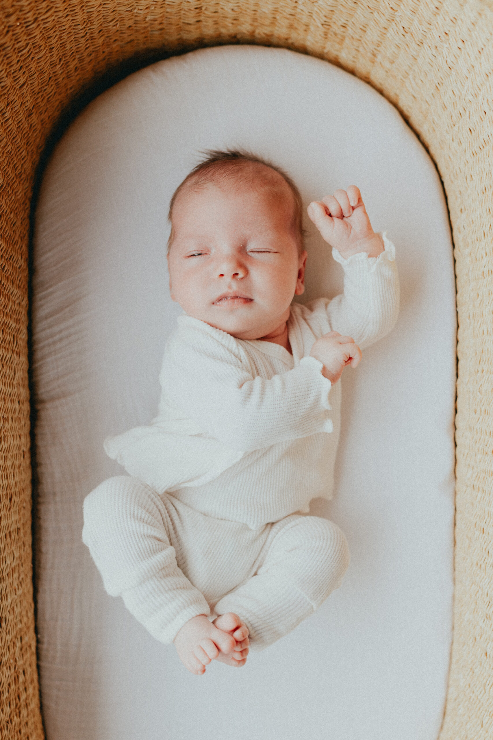 Photo of a newborn baby laying in their bassinet stretching taken for langley newborn photography
