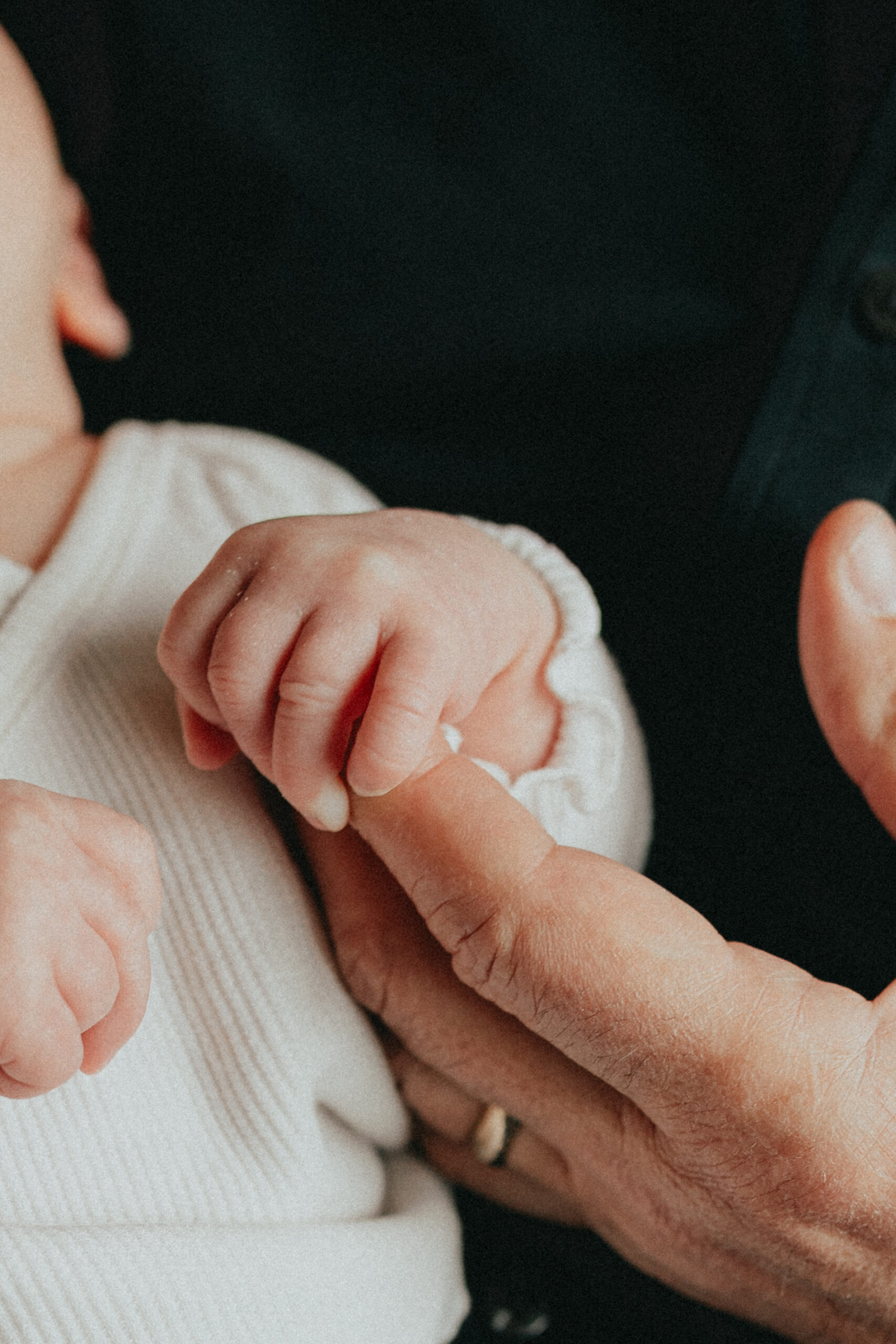 Close up photo of a baby holding the finger of the person holding them taken for lifestyle newborn photography