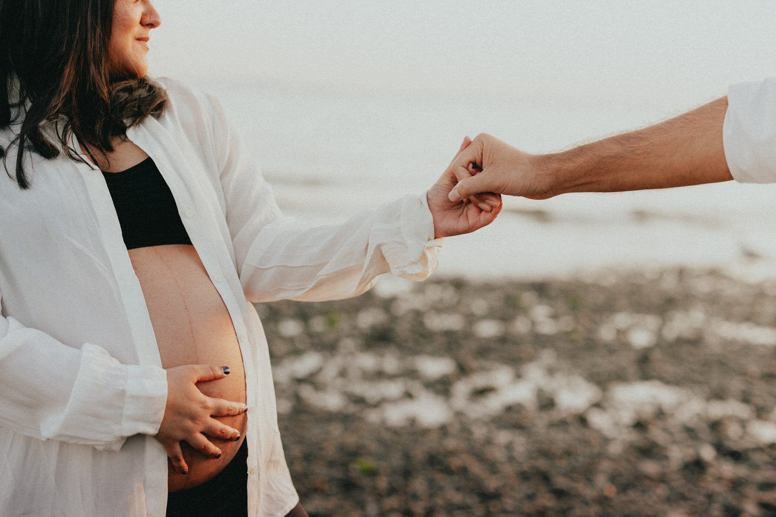 photo of a pregnant woman on a vancouver babymoon, holding her partners hand who is out of frame and you can only see her holding her baby bump