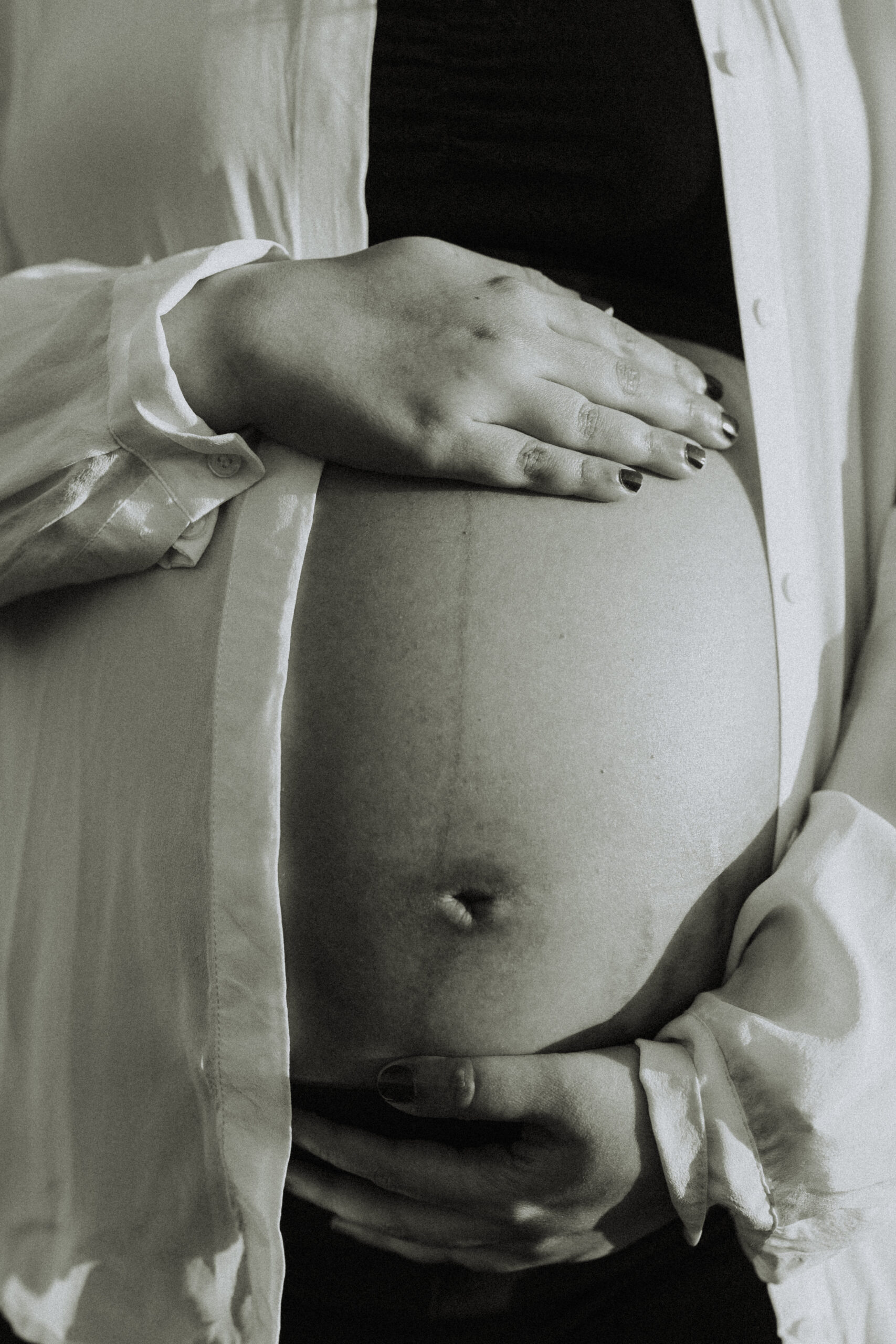 black and white close up photo of a pregnant woman holding her baby bump