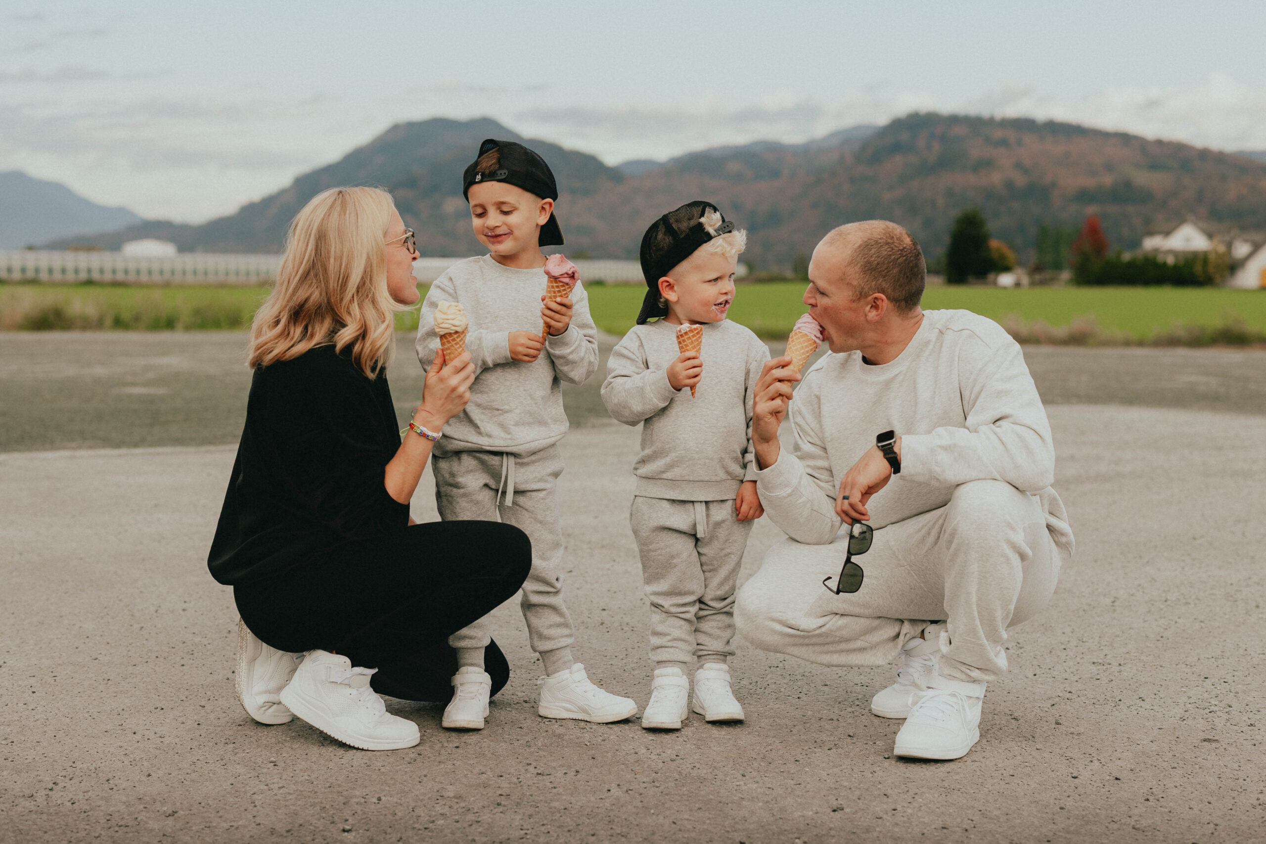 Photo of a family of 4 all eating ice cream together while looking at each other and smiling