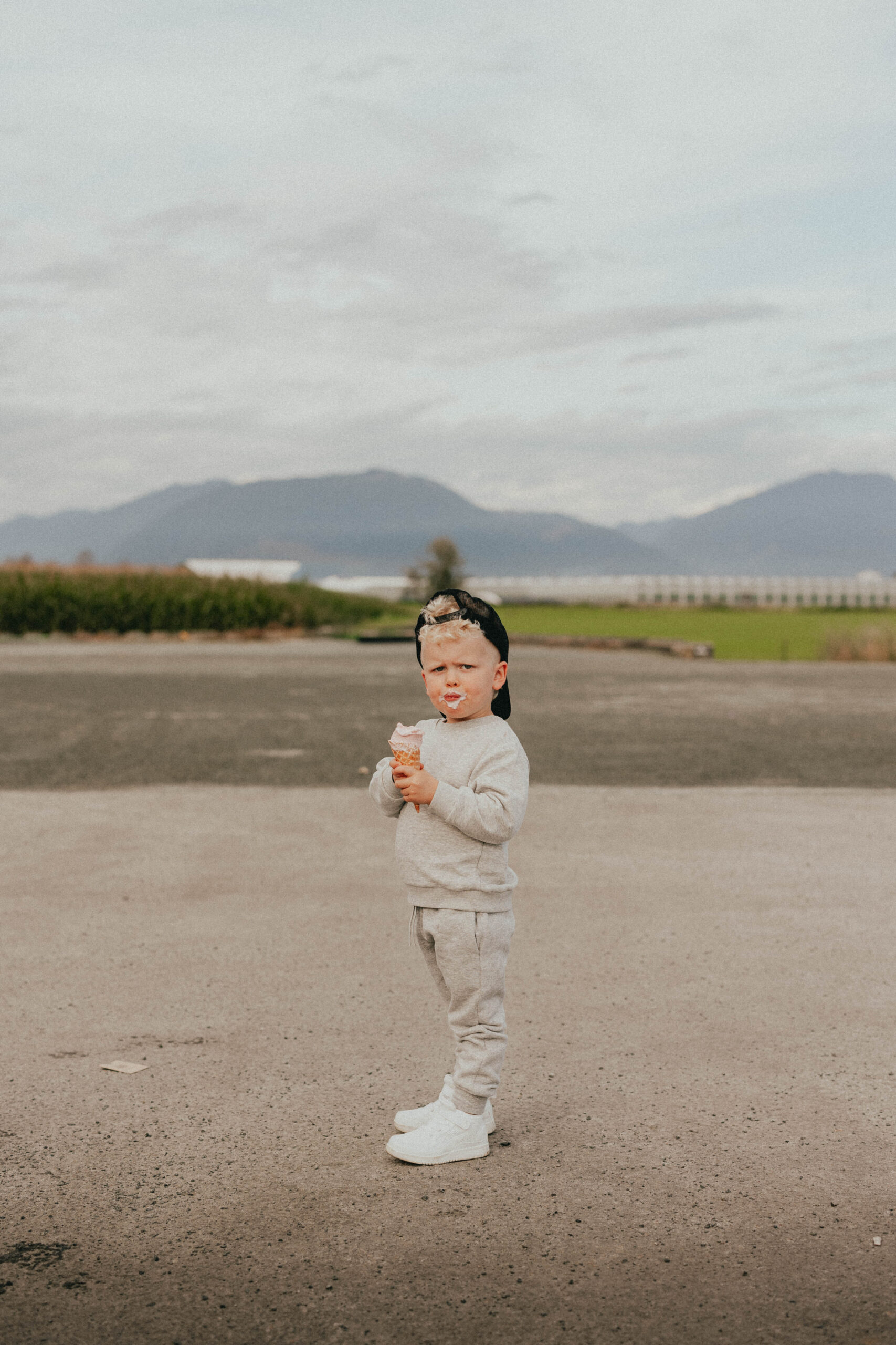 Photo of a boy standing and looking at the camera while holding an ice cream cone