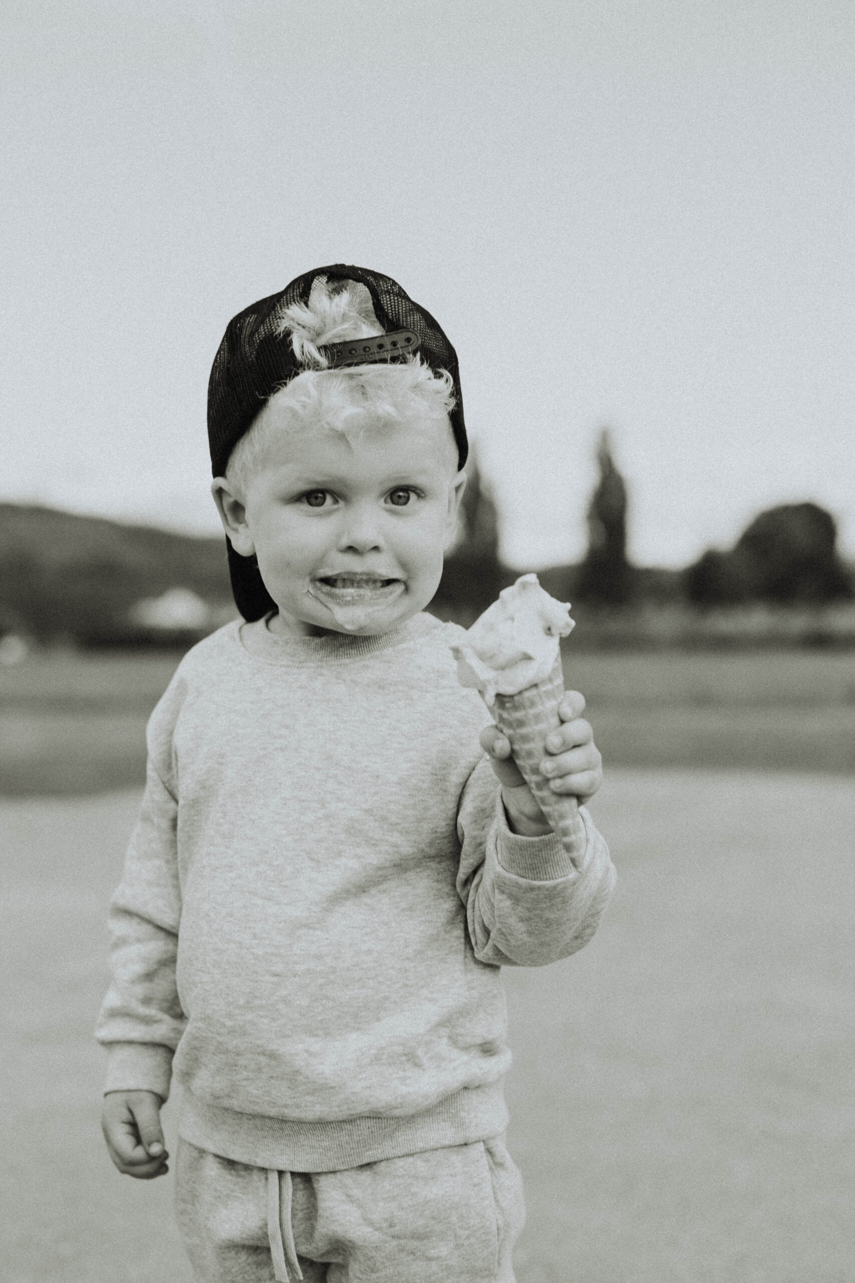 Black and white photo of a boy looking at the camera  smiling while holding an ice cream cone