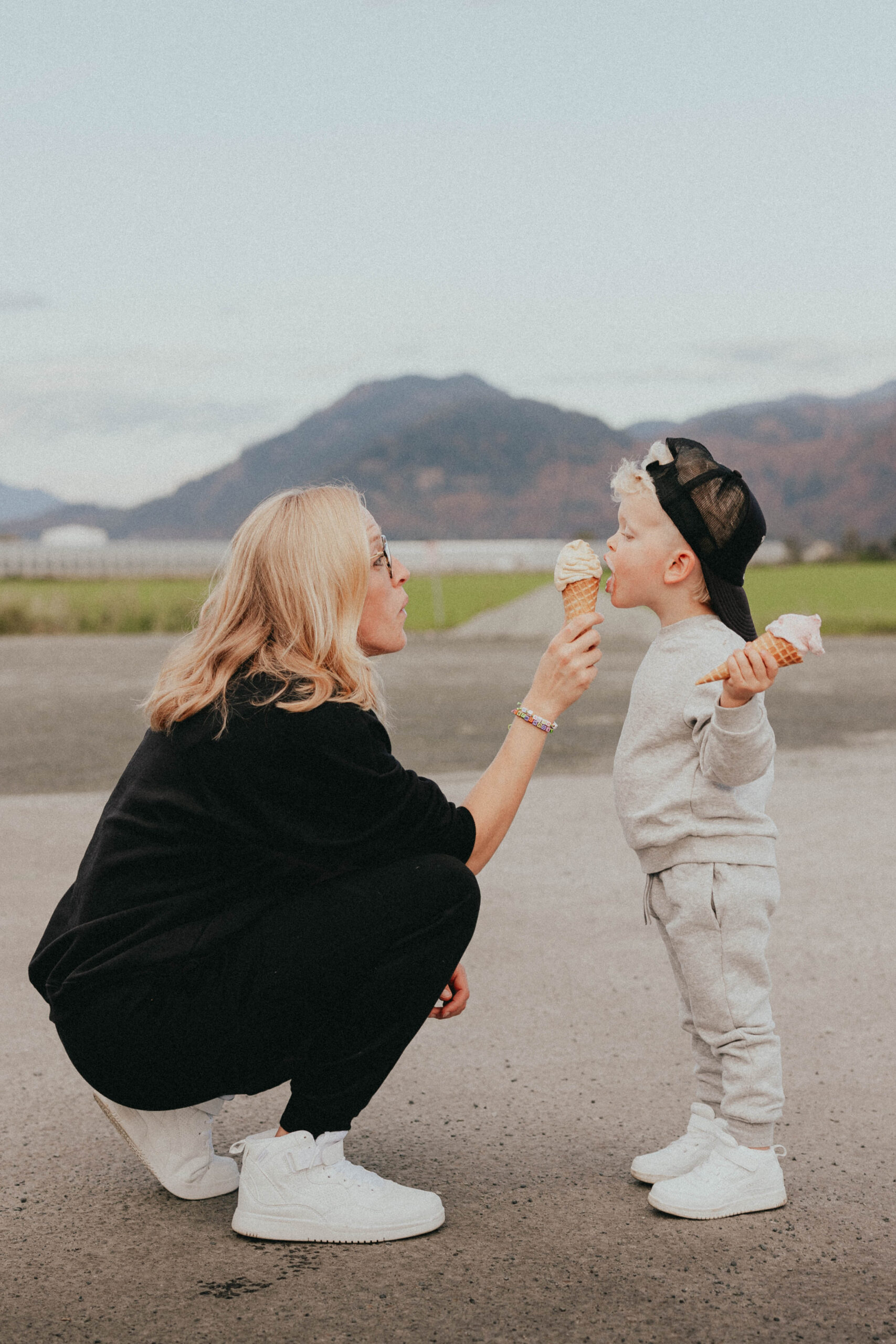 Family Photos of a mom standing in front of her toddler son letting him lick her ice cream while he holds his own in his hand
