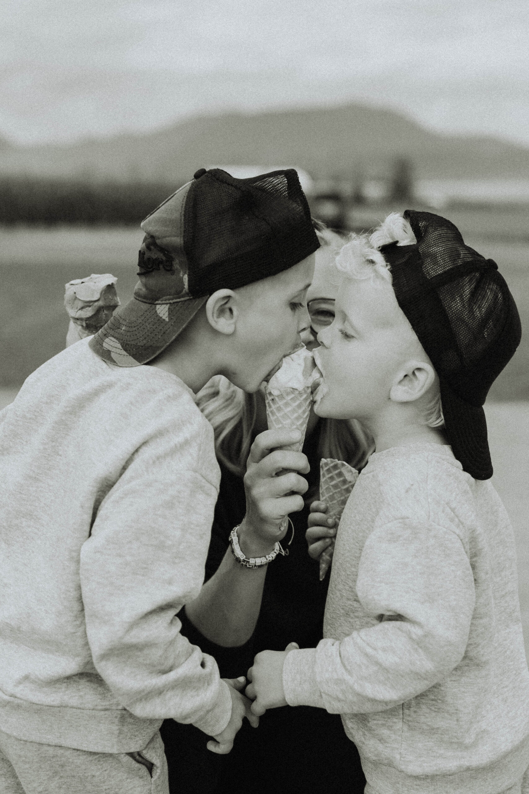 Black and white family photos of 2 boys sharing an ice cream cone that their mom is holding