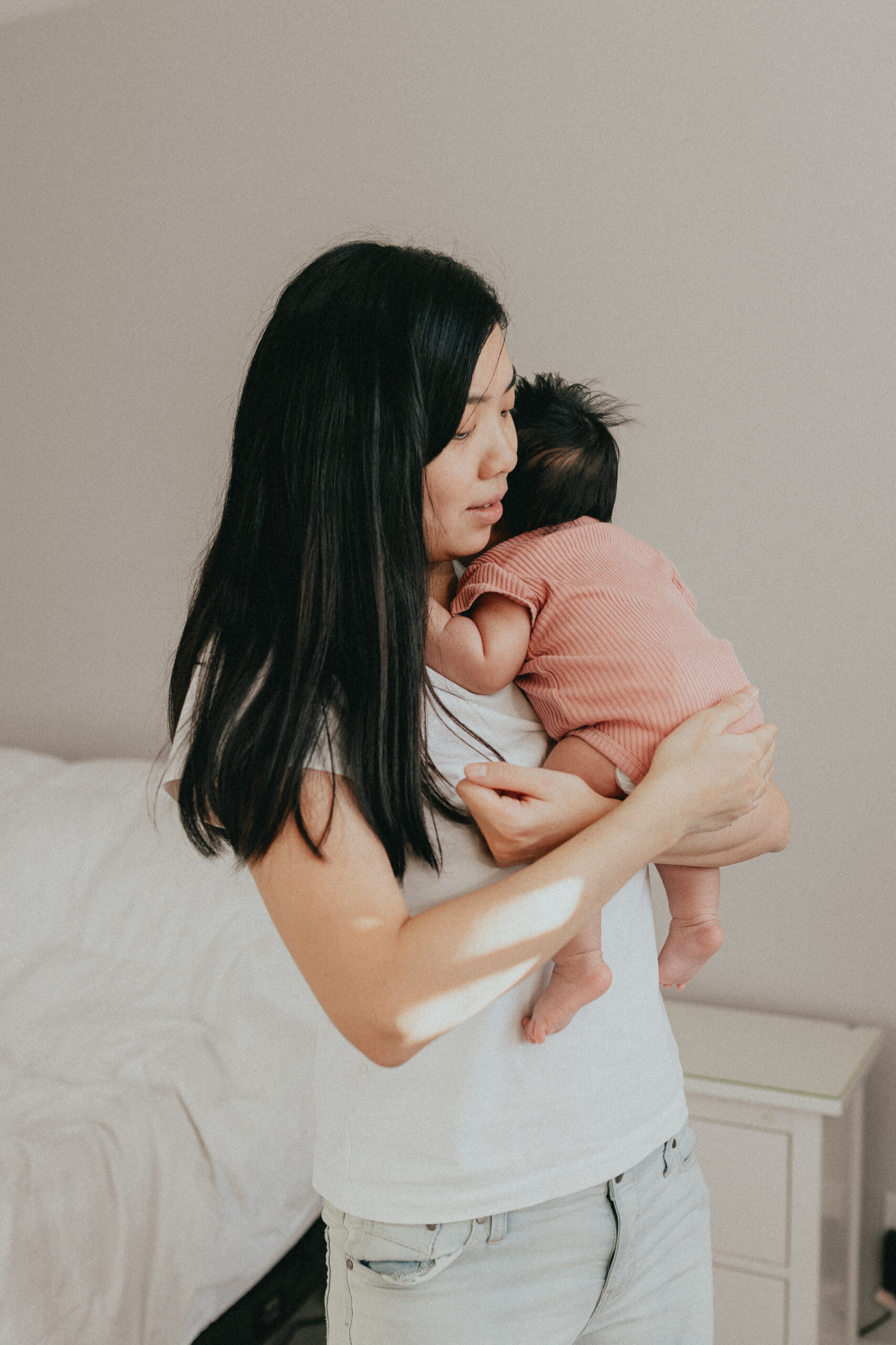 A mother holding her newborn baby up over her shoulder and rocking her to calm her