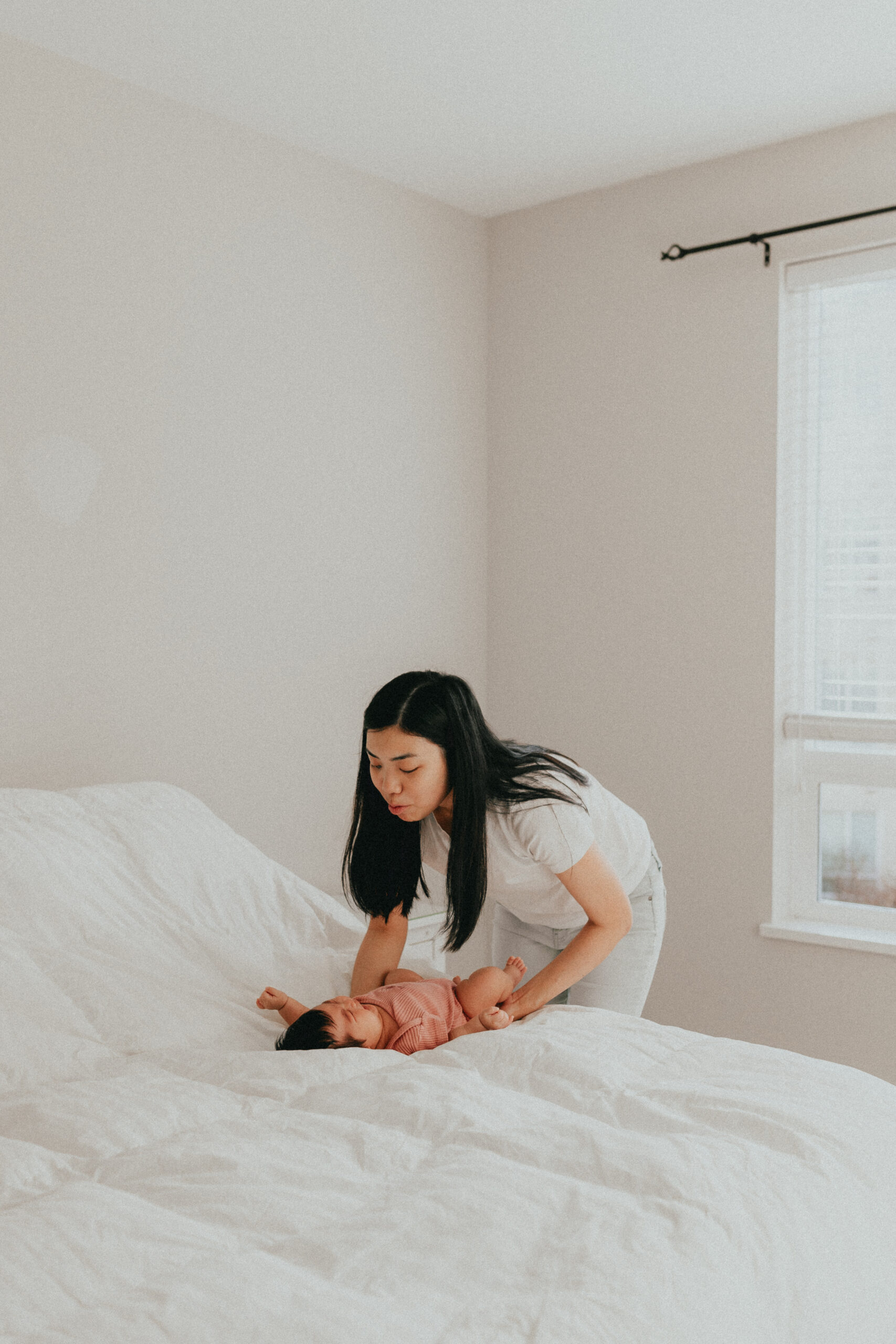 Photo of a mom picking up her newborn baby off the bed