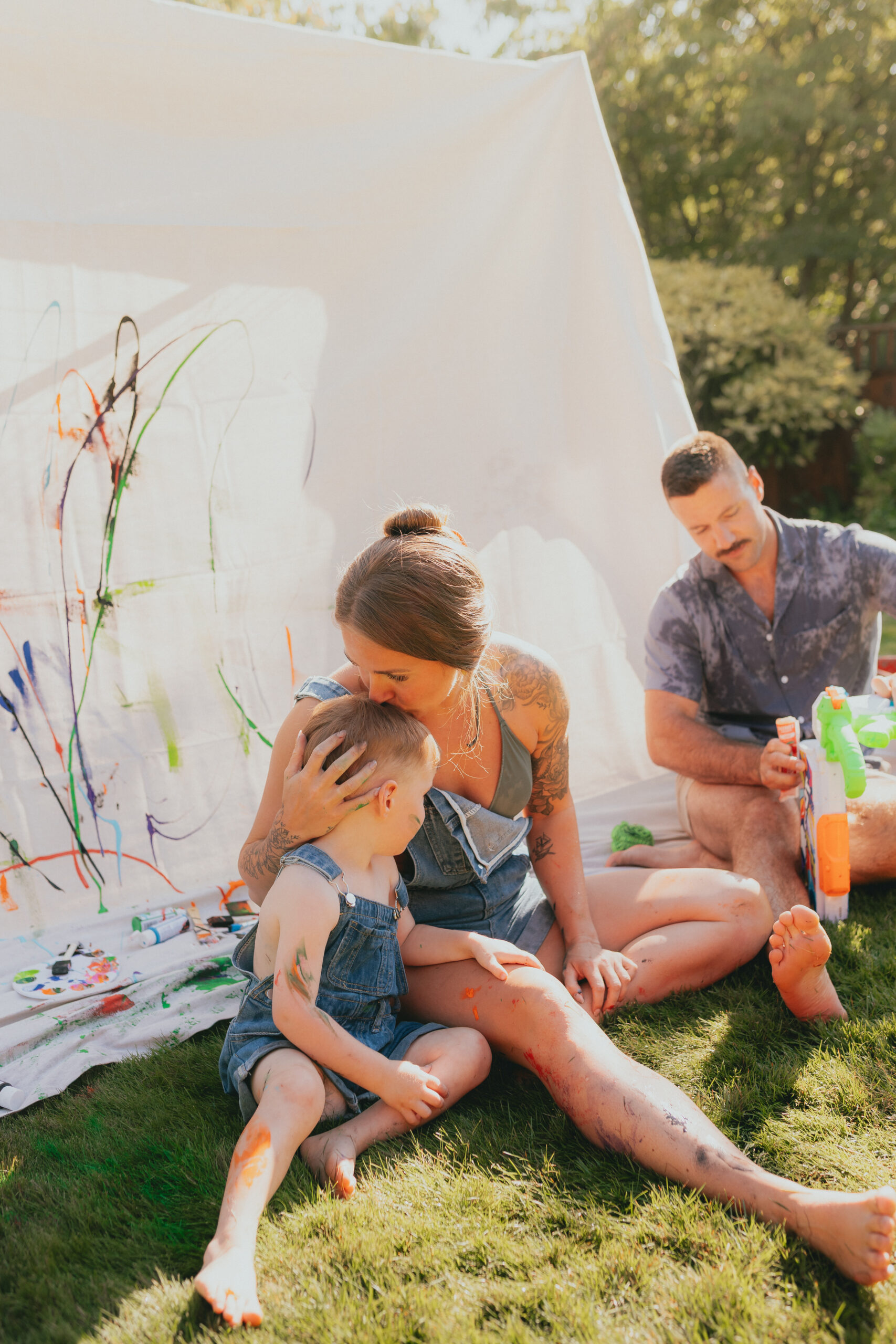 Photo of a mom and son sitting beside each other while the mom kisses her young son on the head