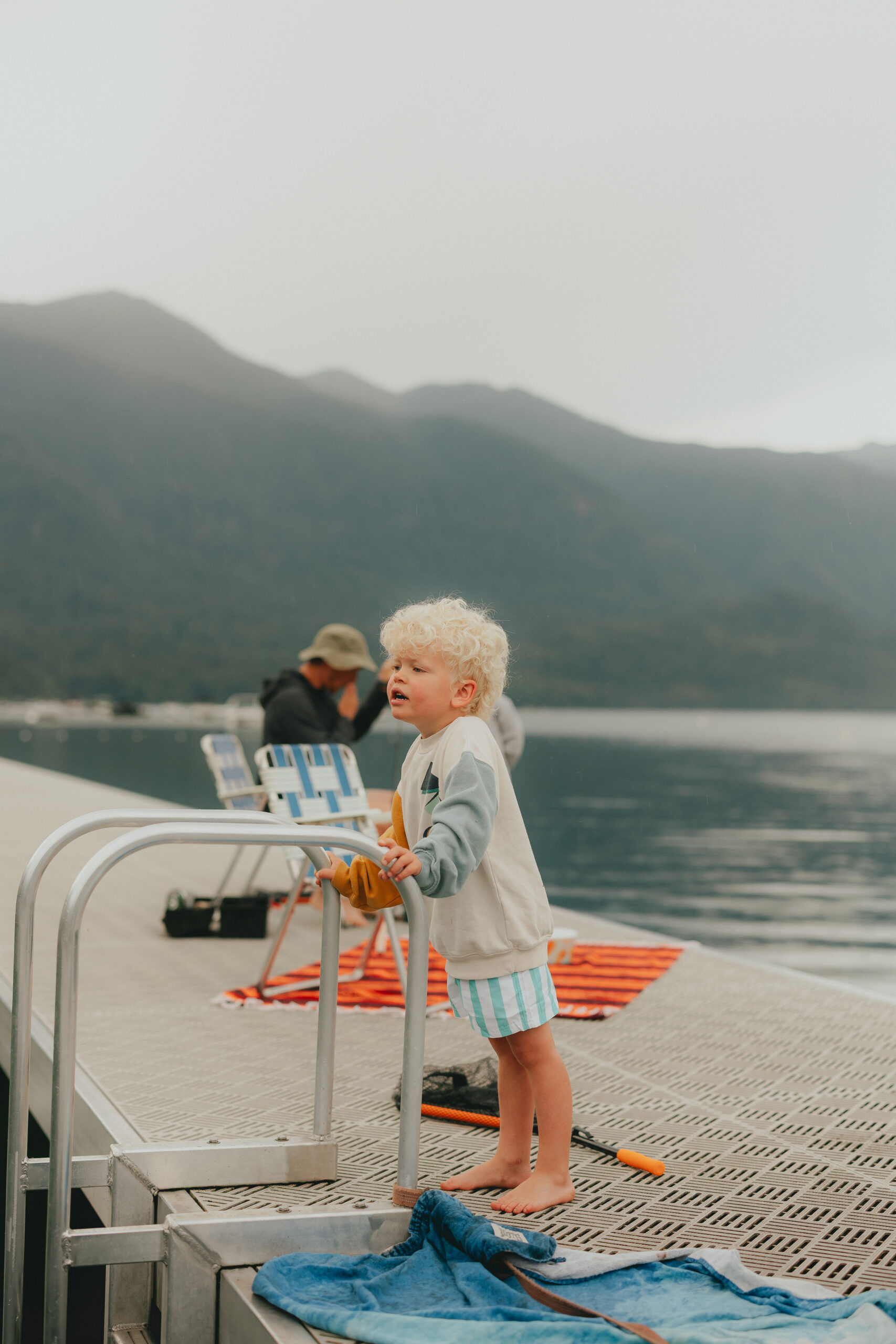 Photo of a boy leaning on the ladder rails of a dock looking off camera for his mom taken by a chilliwack photographer