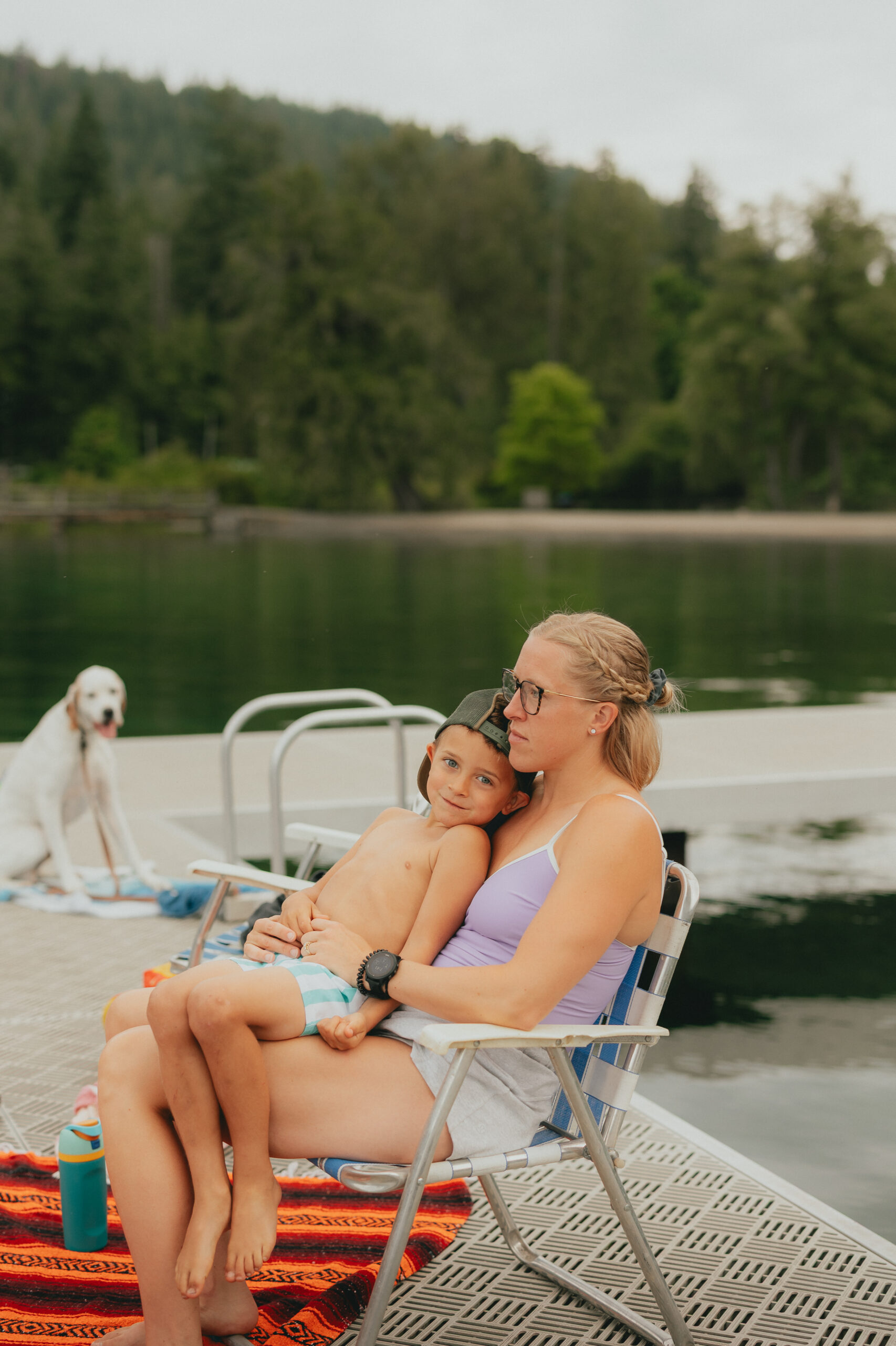 Little boy sitting on his moms lap looking at the camera while the mom looks off into the distance