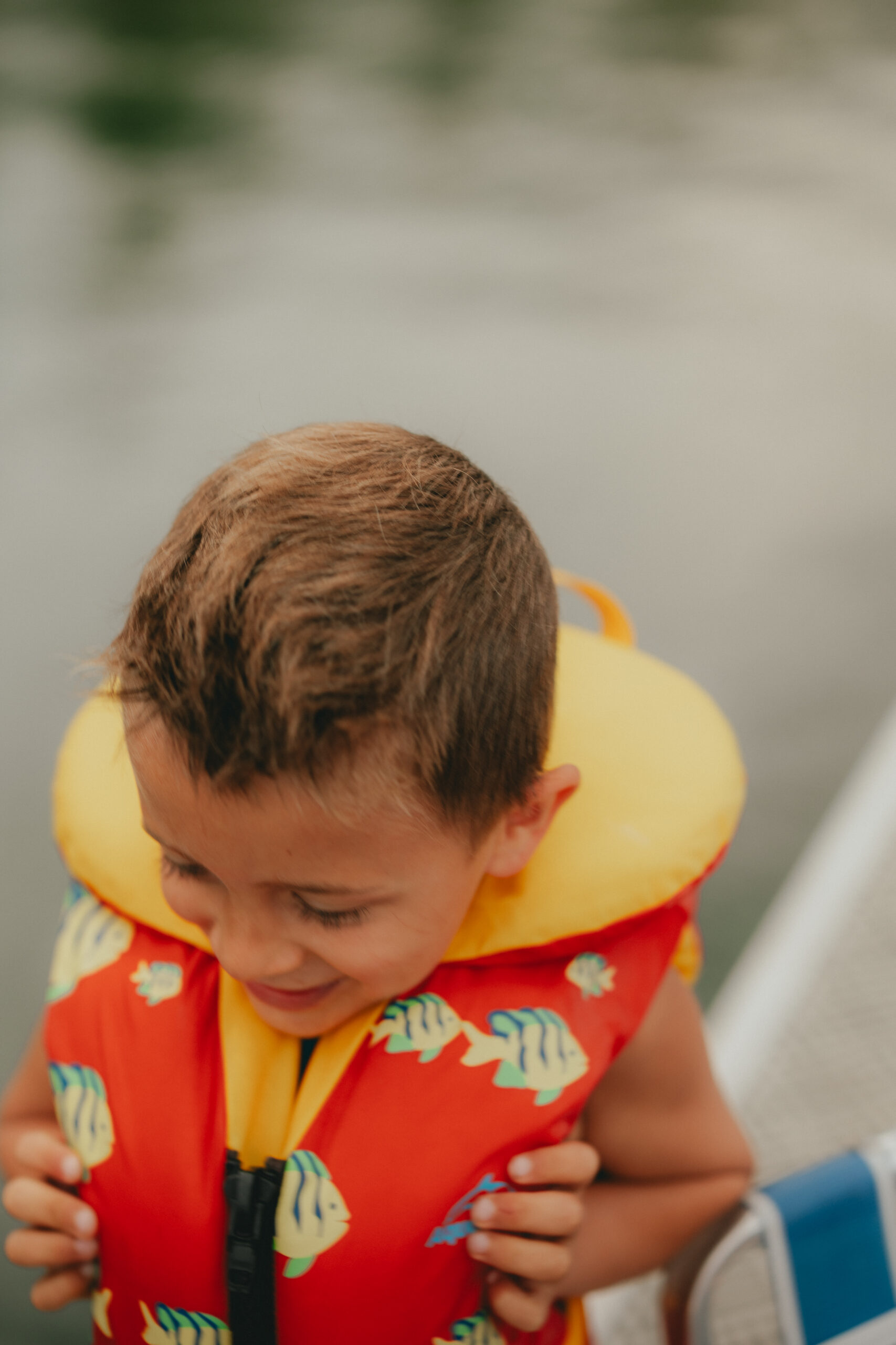 Blurry photo of a little boy running by the camera wearing a lifejacket