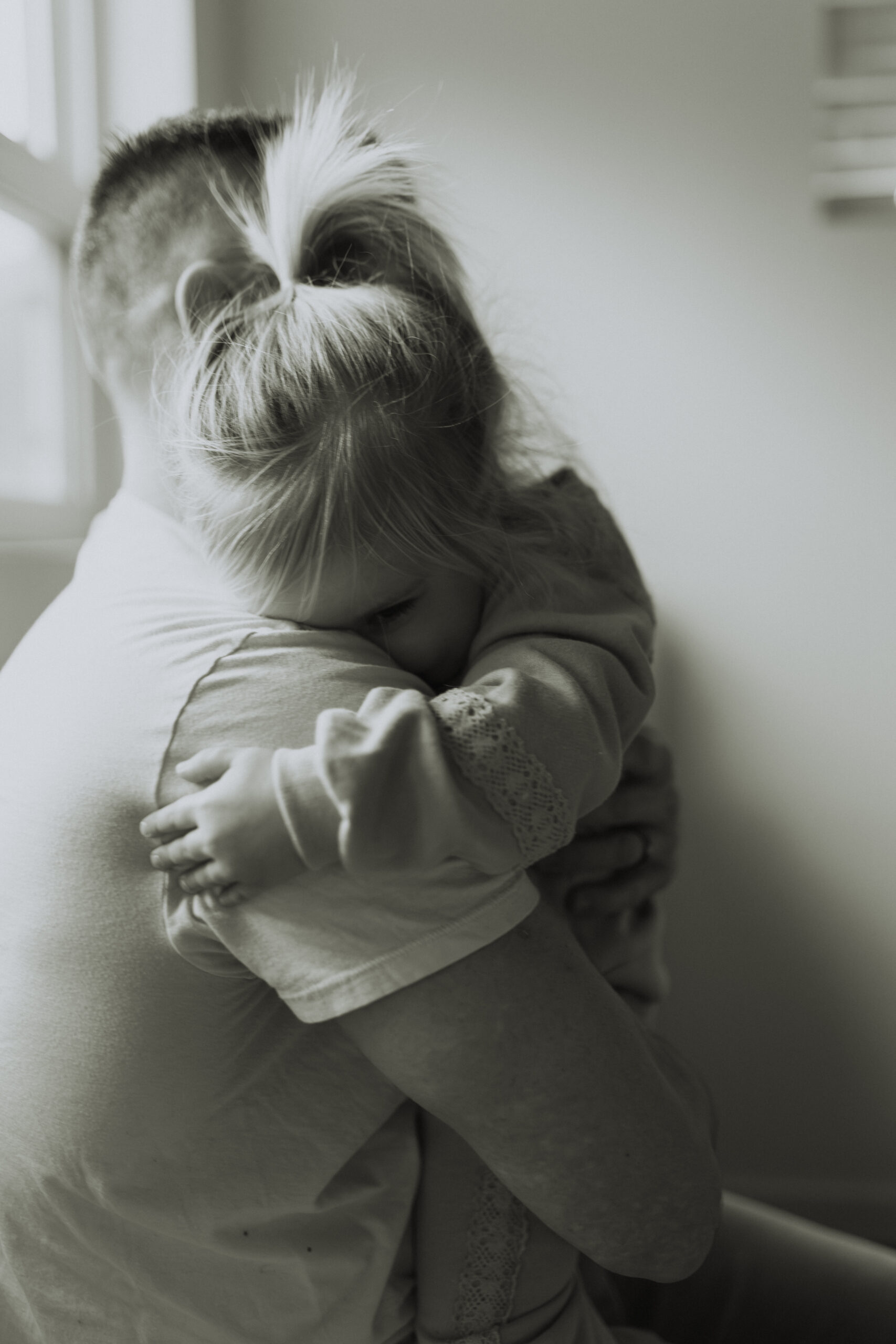 black and white photo of a little girl hugging her dad with her face buried in his shoulder with her eye just peeking out. Taken by a newborn photographer, Abbotsford B.C.