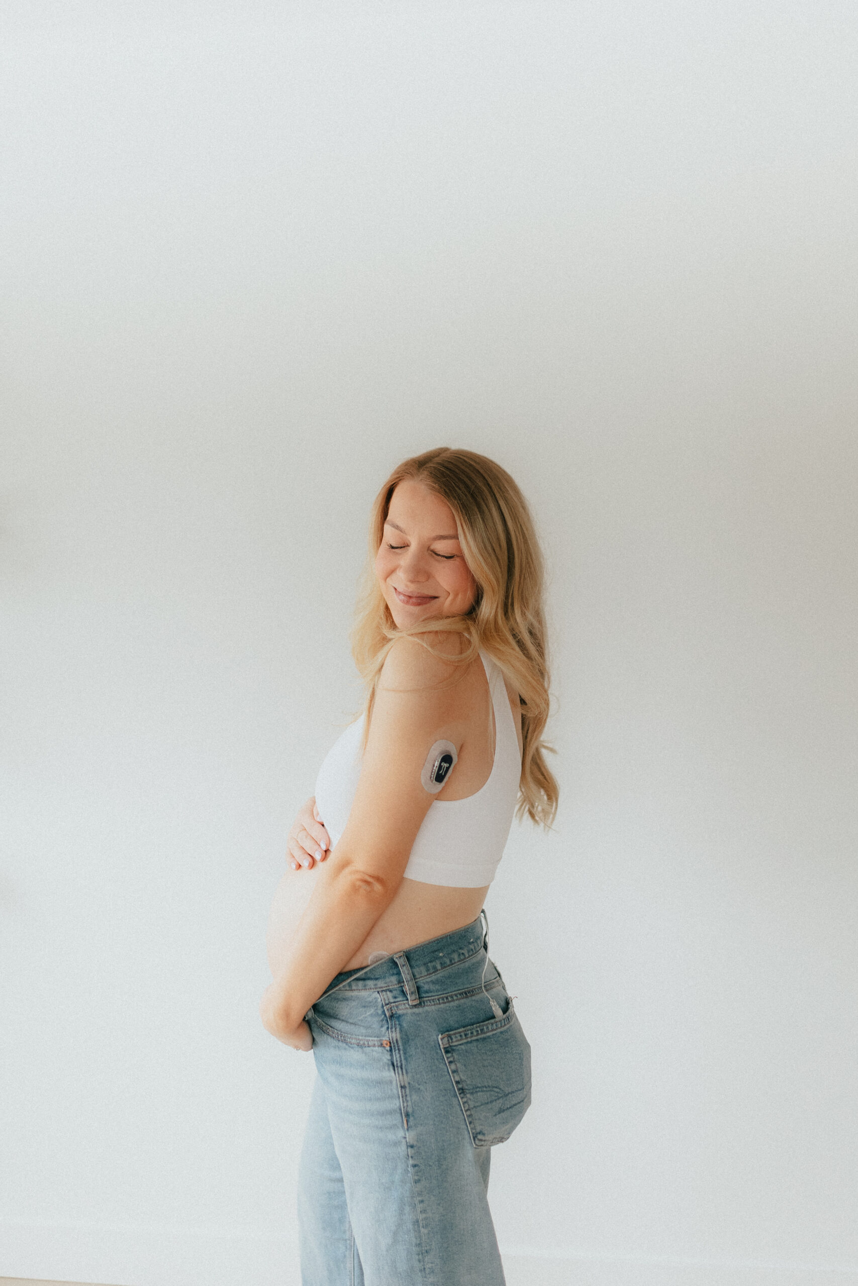 Photo of a pregnant woman holding her baby belly while looking over her shoulder with her eyes closed taken by a maternity and newborn photographer in abbotsford